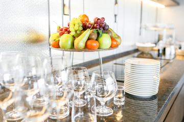 Breakfast in restaurant of hotel. Plate with fruits and berries on a smorgasbord. Many wineglasses. in the background. Bar