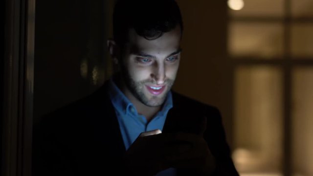 Business man using mobile alone in dark office