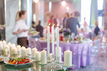 Burning candle. White candles on glass candlesticks stand on tables at luxury wedding reception in restaurant. stylish decor and adorning