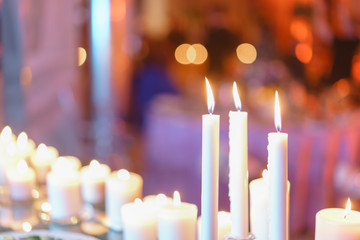 Burning candle. White candles on glass candlesticks stand on tables at luxury wedding reception in restaurant. stylish decor and adorning