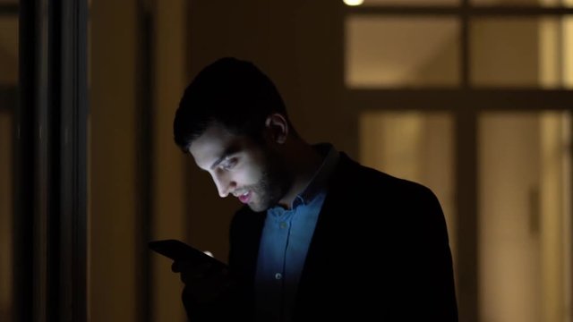 Business man using mobile alone in dark office