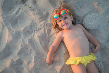 Holiday background, little cute girl on sand and copy space