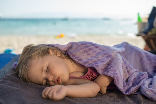 Cute baby is sleeping on the beach at summer day wrapped in towel