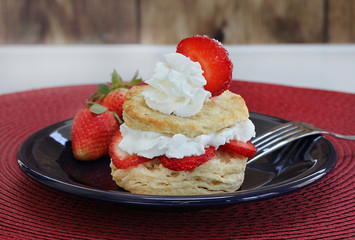 Fresh strawberry shortcake with homemade biscuits and garnished with a sliced strawberry.