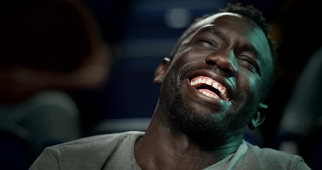 Man laughing uncontrollably while watching a very funny film at the cinema.
