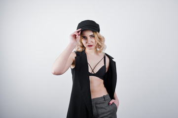 Studio portrait of blonde girl in black wear and cap against white background.