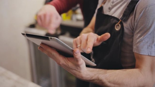 Close up of two waiters hands using digital tablet in cafe