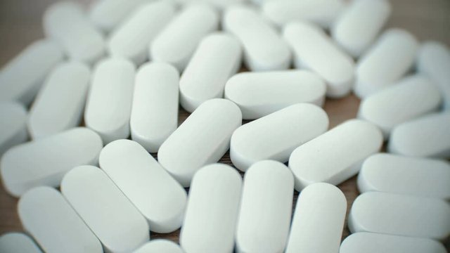 Closeup white oval pills on the table.