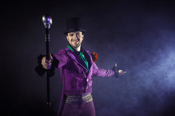 Showman spreading hands, show begins. The guy in the purple camisole and the cylinder.