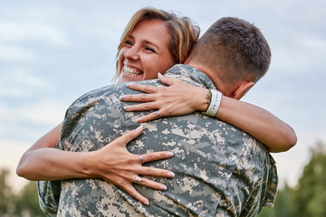Happy woman hugging his husband came back from army. Smiling cheerful caucasian girlfriend embracing a soldier. - Powered by Adobe
