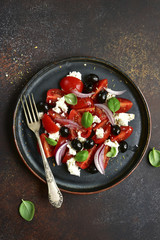Tomato salad with feta cheese, black olives and red onion.Top view with copy space.