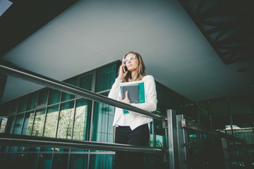 Fototapeta premium young blonde business woman outdoor in the city with smart phone