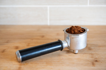 Filter holder with ground coffee on wooden table