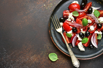Tomato salad with feta cheese, black olives and red onion.Top view with copy space.