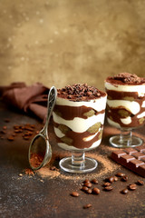 Traditional italian dessert tiramisu with chocolate sauce in a glass.