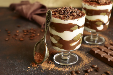 Traditional italian dessert tiramisu with chocolate sauce in a glass.