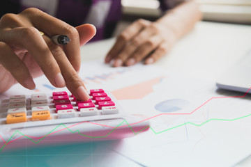 Fototapeta premium Close up woman working at home office. yong businessmen calculate about cost and stock market or forex graph suitable for financial investment.