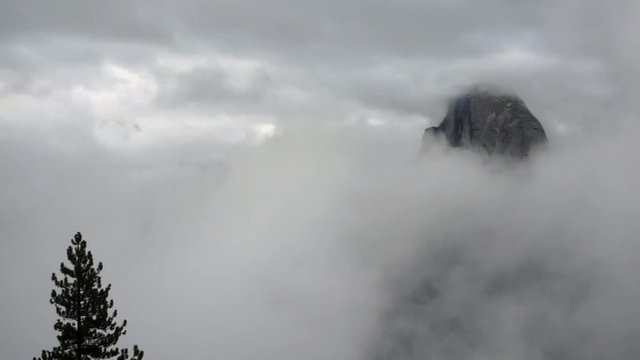 The fog meanders around the rock face called Half Dome before clearing for a moment to allow viewing in Yosemite National Park