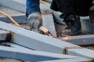 Asian worker making sparks while welding steel