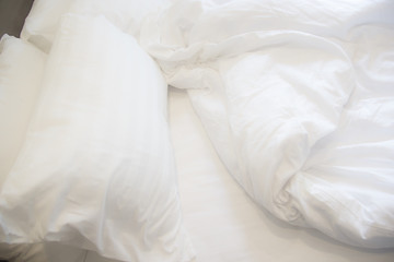 White pillow on the bed with blanket, bedding sheet and shadow soft focus