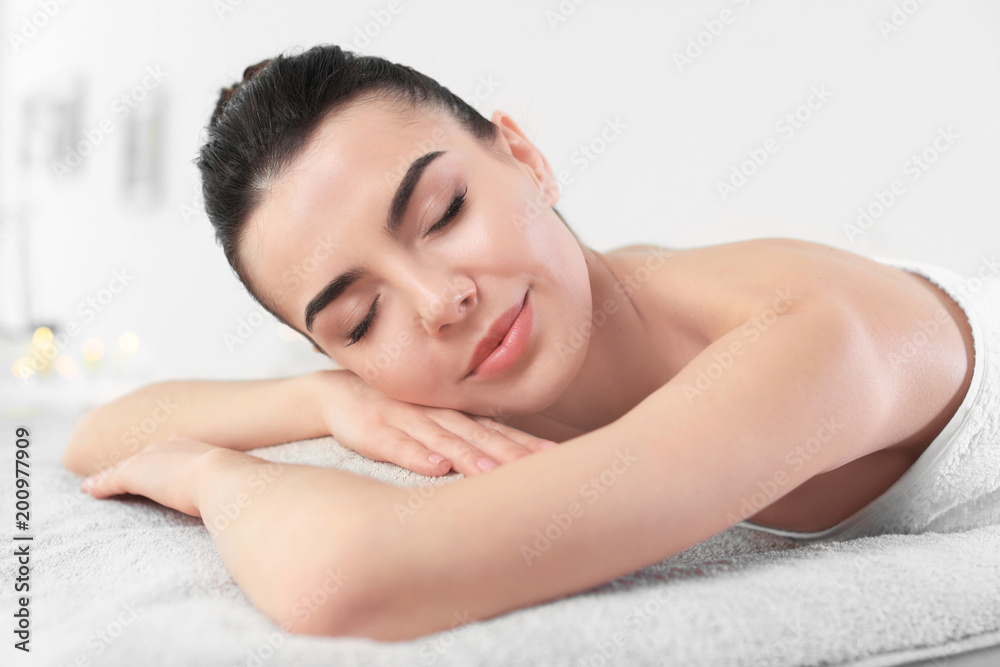 Poster Young woman lying on massage table in spa salon