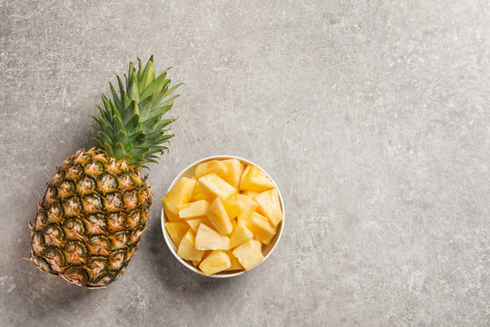 Fresh whole and sliced pineapple on grey background