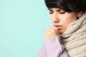 Young woman coughing on color background