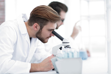 Naklejka premium Serious clinician studying chemical element in laboratory