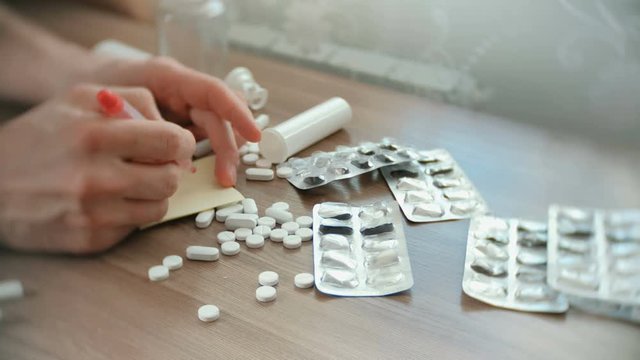 Men's hands slip off the table with white pills, blisters and tablets.