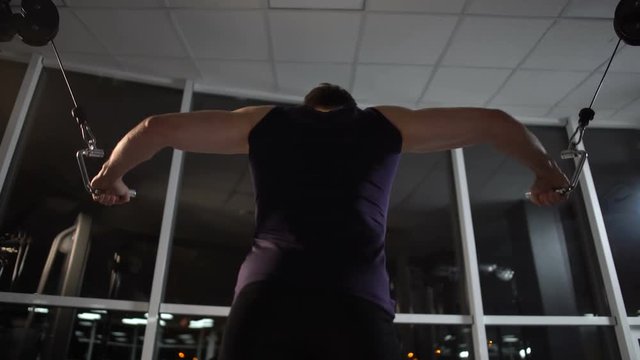 Persistent sportsman trains chest muscles on cable machine in spite of late time