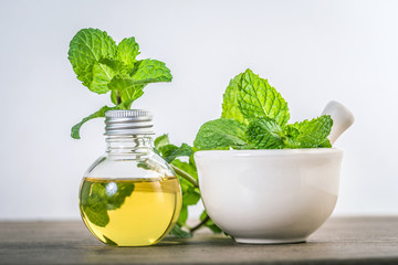 Aroma essential oil from a peppermint in the bottle on the table with fresh green mint leaf