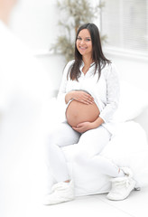 portrait of pregnant woman sitting on the couch in the new apartment.