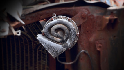 A close up view of a rusted car horn in a salvage yard.