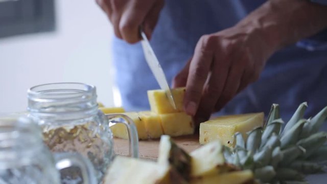 Chef hands cut pineapple on wooden cutting board. Man preparing fruit dessert