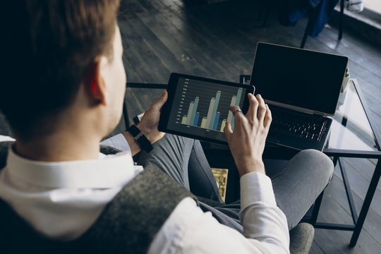Young businessman operating at tablet his work, sitting in a chair in office.