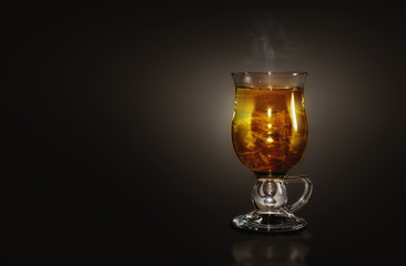 Glass with a hot herbal tea in a dark background