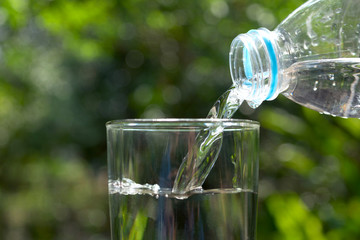 Pour water in the glass under green background.