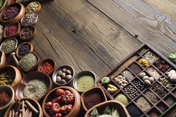 Variety of colorful dry spices  and herbs in teakwood bowls. Rustic wooden kitchen table. Indian and thai ingredients. 