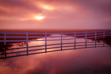 Cloudy Sunrise Reflection with Fence and water
