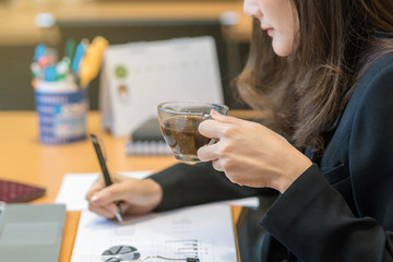 Closeup businesswoman hand drinking coffee when working with with computer laptop and office supplies in modern office or meeting room, Business and worker concept