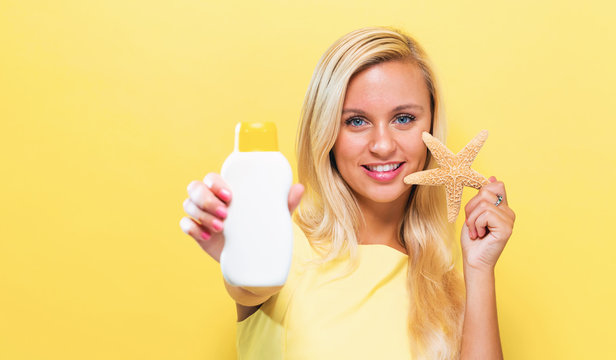 Young woman a bottle of sunblock on a yellow background
