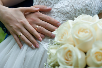 Obraz na płótnie Canvas the bride's hand with the wedding ring lies on the groom's hand with the wedding ring and in the foreground the bride's bouquet