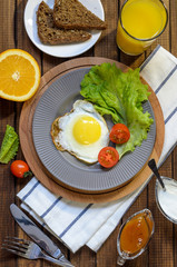 English Breakfast: fried egg, juice, cherry tomatoes, lettuce, grain bread, sauce, top view.