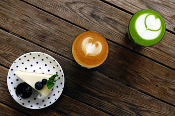 A cup of green tea matcha latte and cup of latte art coffee on wooden background