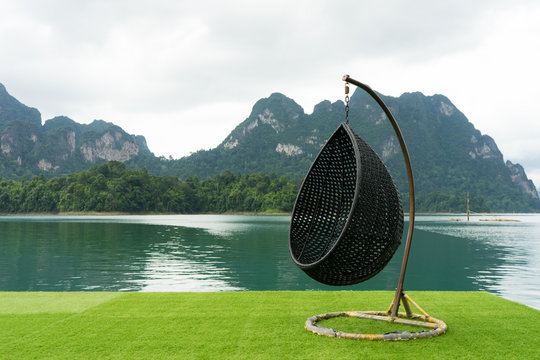 Wicker hanging chair swing hanging on a chain with beautiful mountains landscape