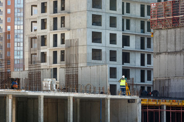 The builder in yellow overalls makes a topographic survey against the background of a concrete...