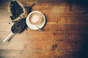 cup of coffee, coffee beans, bag on a wood table on a wooden background