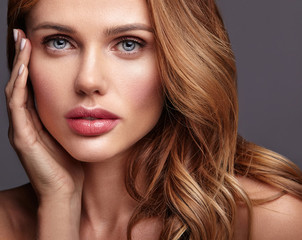 Fototapeta premium Beauty fashion portrait of young blond woman model with natural makeup and perfect skin posing in studio. Touching her face