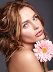 Obraz na płótnie Canvas Beauty fashion portrait of young blond woman model with natural makeup and perfect skin with bright pink gerbera flower posing in studio.