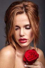 Fototapeta na wymiar Beauty fashion portrait of young blond woman model with natural makeup and perfect skin with beautiful rose posing in studio